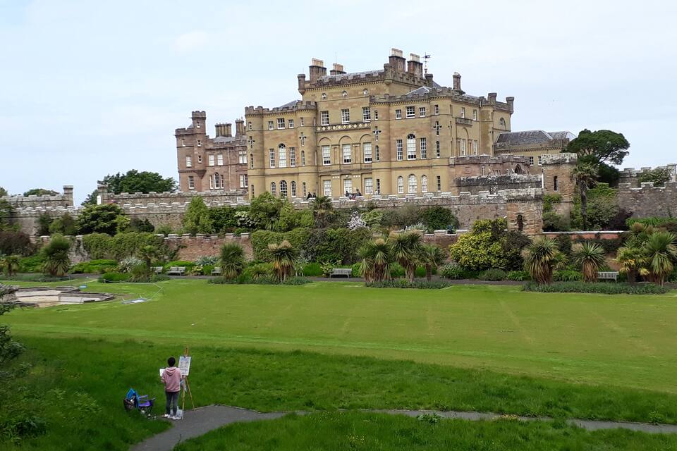 Un edificio grande e histórico con un jardín bien cuidado al frente.