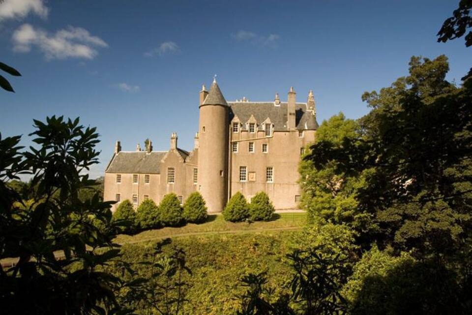 A large castle with multiple towers and a well-maintained garden.