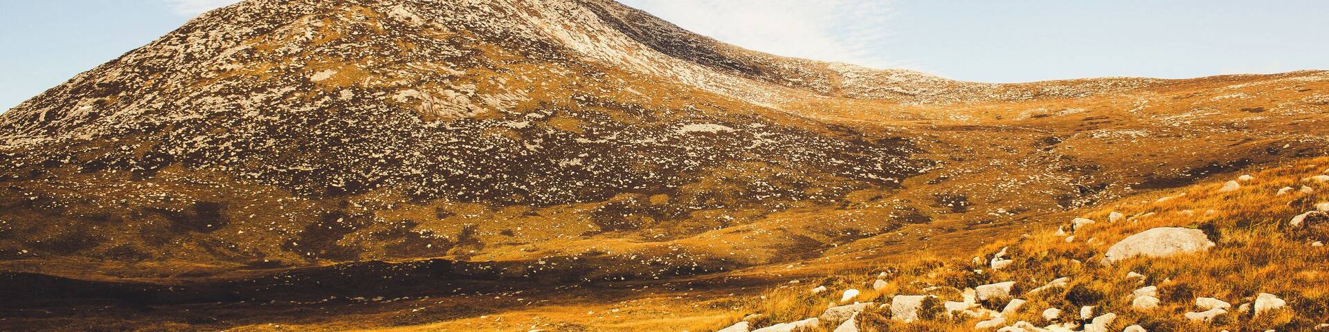 A mountain with rocky terrain and grassy fields.
