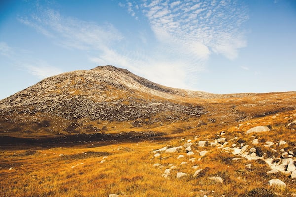 Ein Berg mit felsigem Gelände und grünen Wiesen.