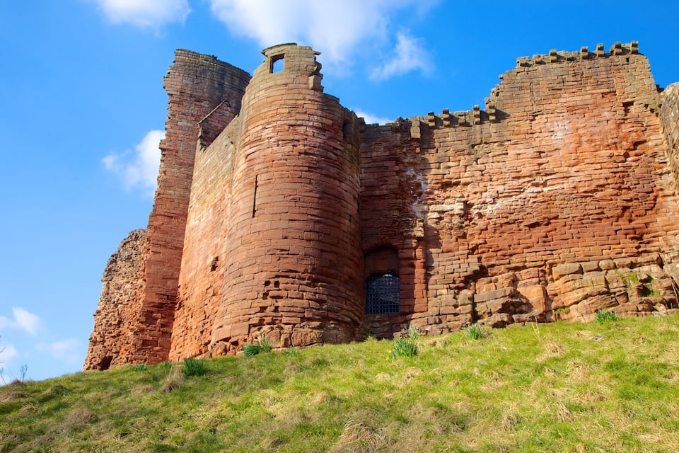 Un vaste château ancien, construit en briques, doté de hautes tours cylindriques et d’un mur partiellement intact.