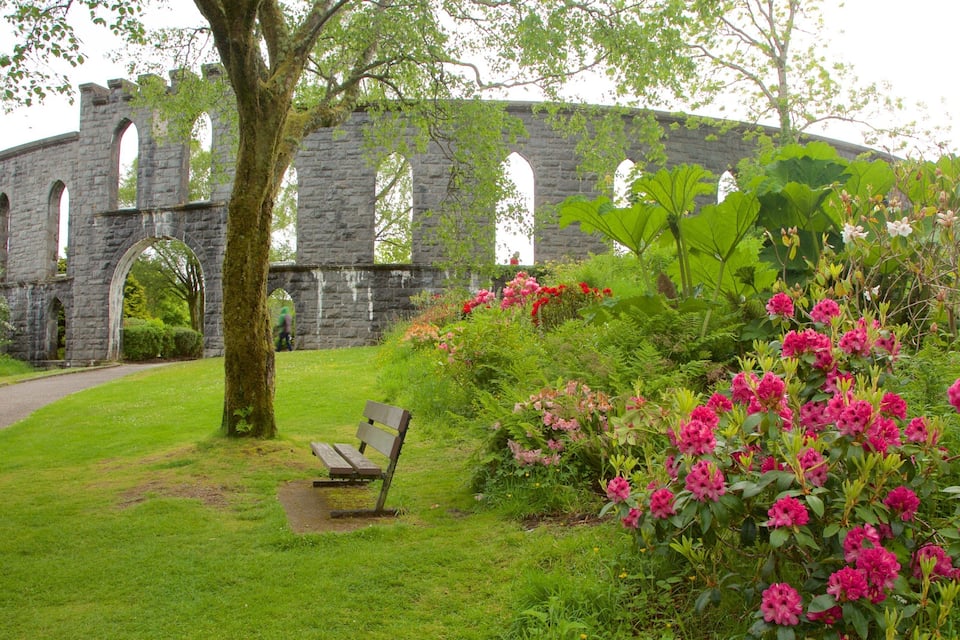 A stone arch bridge, lush greenery, and vibrant pink flowers.