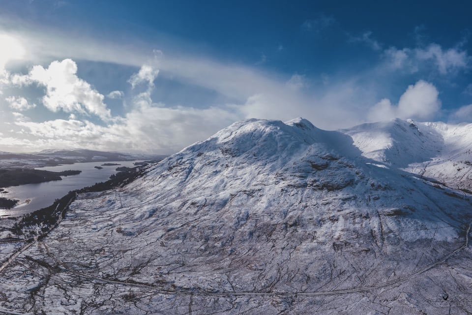A snow-covered mountain with a lake and a clear sky.