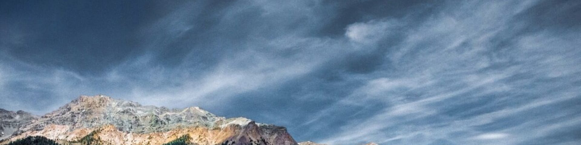 Une chaîne de montagnes avec des vallées verdoyantes et un ciel nuageux.