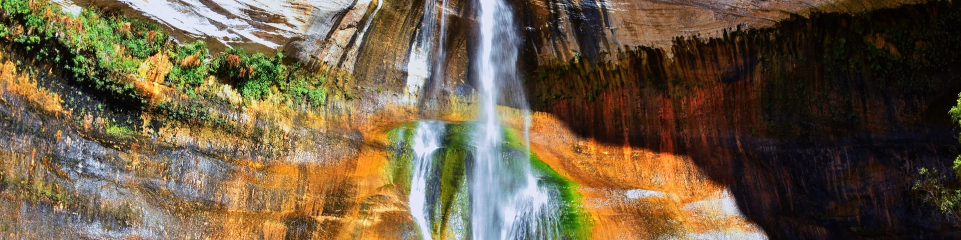 A waterfall cascading into a pool surrounded by multicolored rock formations.