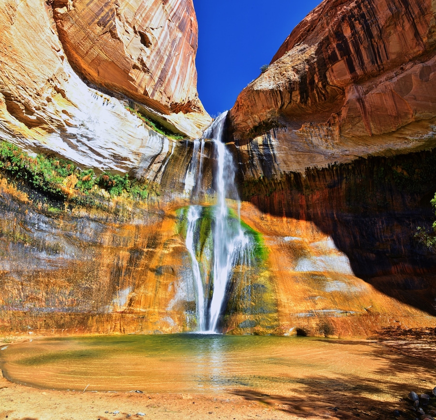 A waterfall cascading into a pool surrounded by multicolored rock formations.