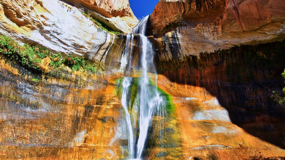 A waterfall cascading into a pool surrounded by multicolored rock formations.