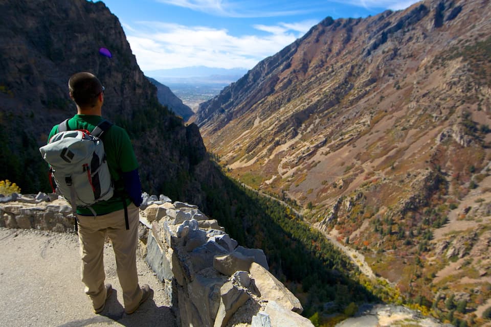 A hiker on a rocky trail with a mountainous landscape in the background.