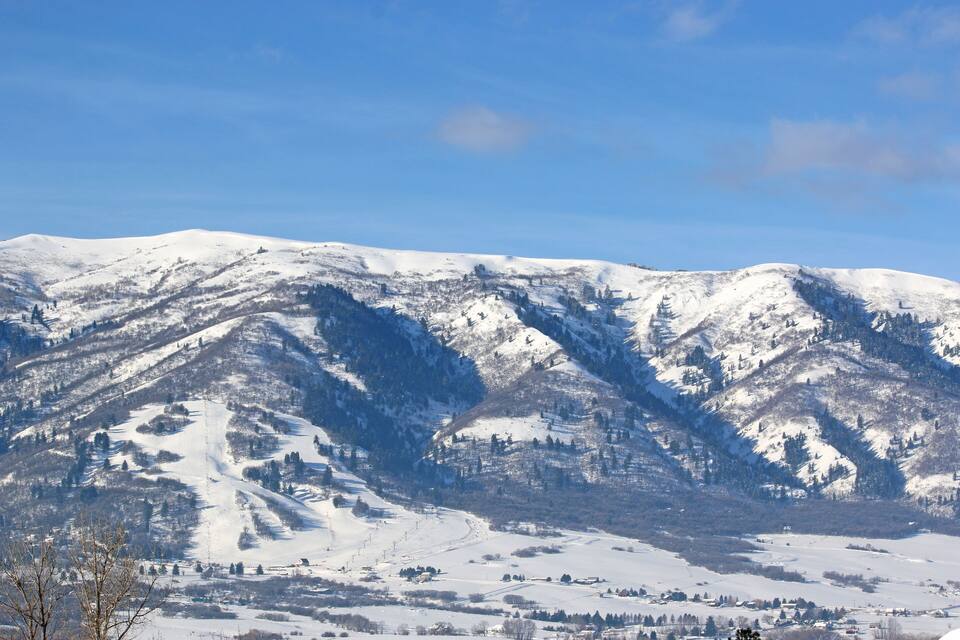 A snow-covered mountain range with ski slopes and a clear blue sky.
