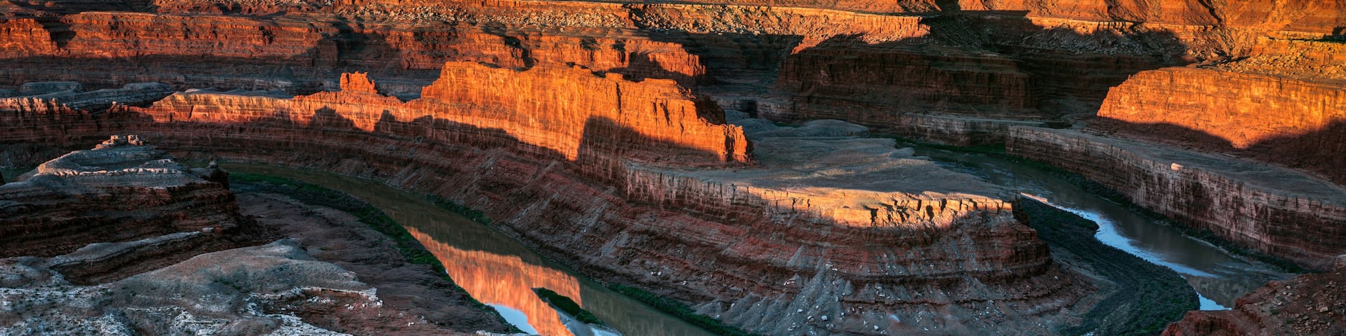 A canyon with layered rock formations and a river.