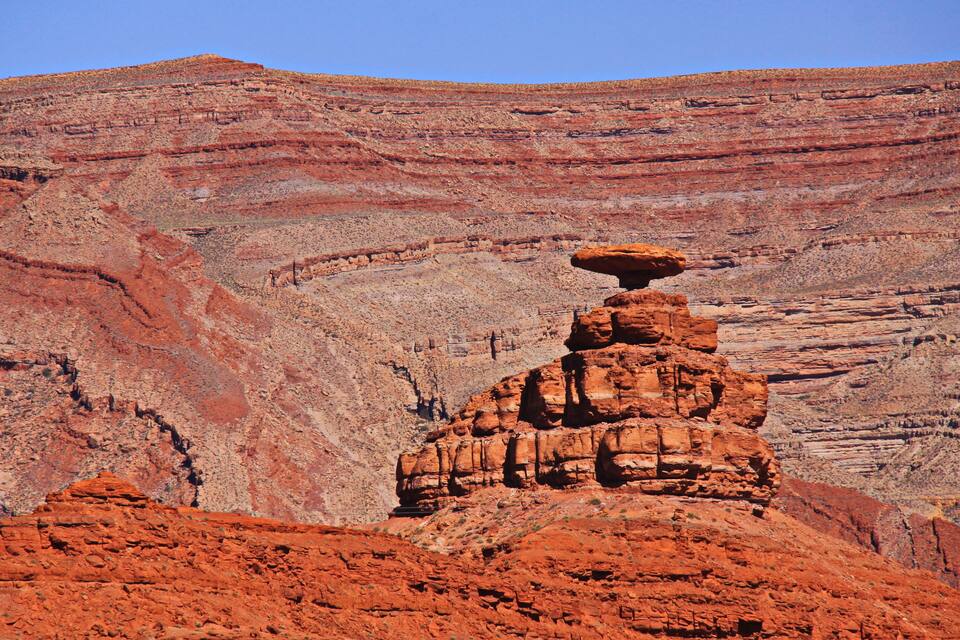 A red rock formation with a balanced rock structure in a canyon.