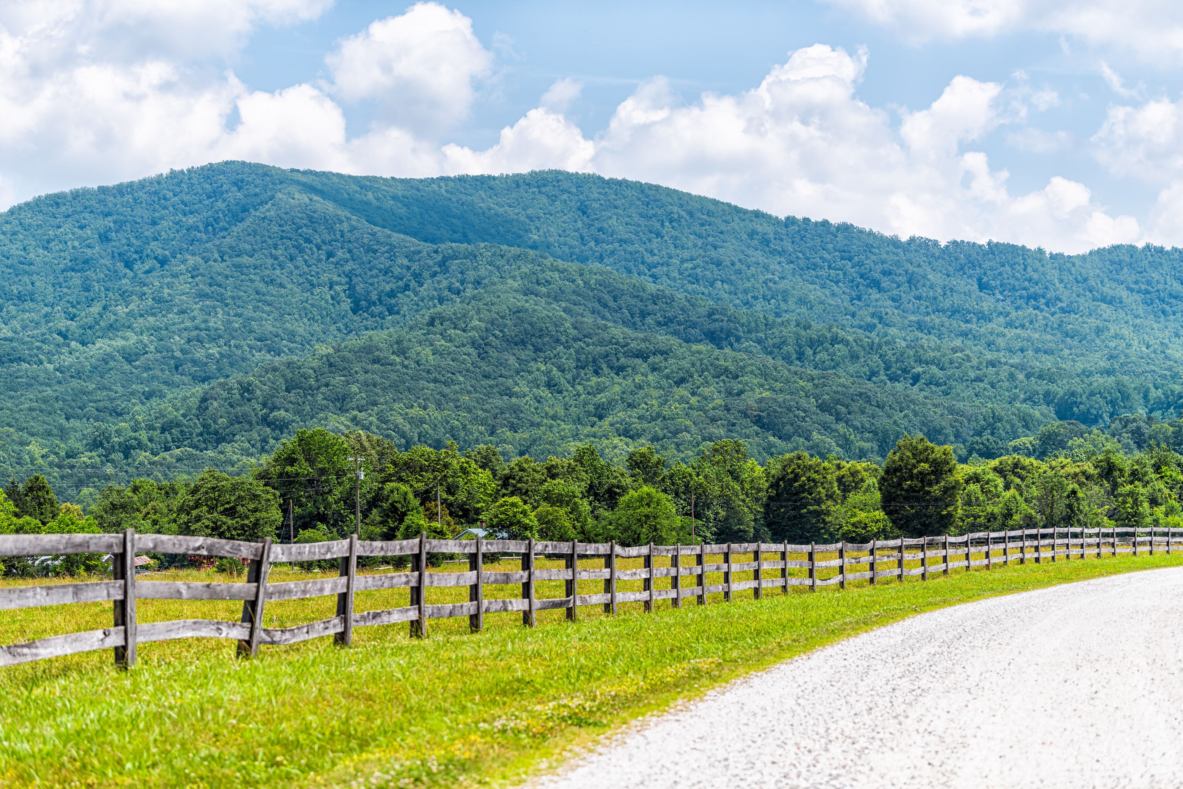 Farm road wooden fence in Roseland, Virginia near Blue Ridge parkway mountains in summer with idyllic rural landscape countryside in Nelson County