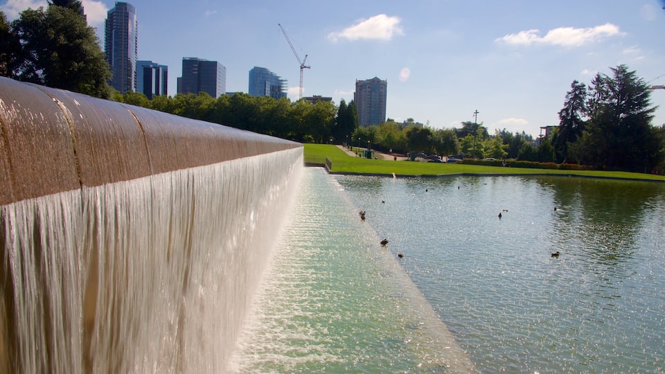 Una cascada grande en un parque, con el horizonte de una ciudad al fondo.