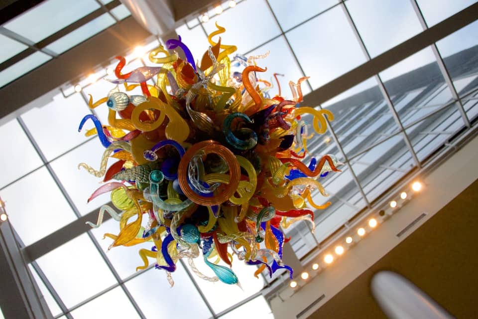 A colorful glass chandelier in a building with large windows.