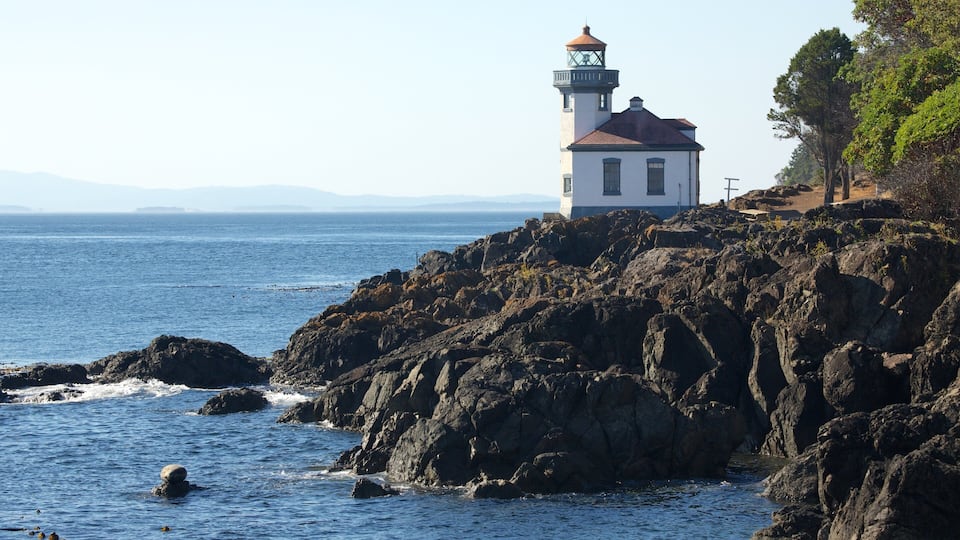A lighthouse on a rocky coastline with the ocean in the foreground.