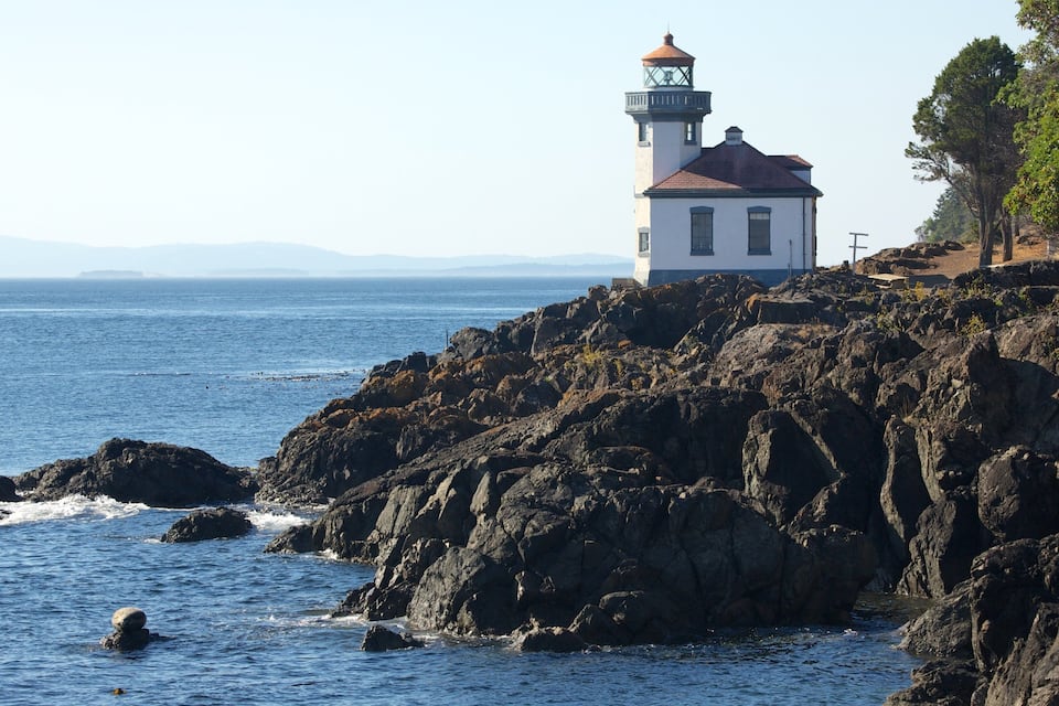 Un faro sobre una costa rocosa, con el océano al frente.
