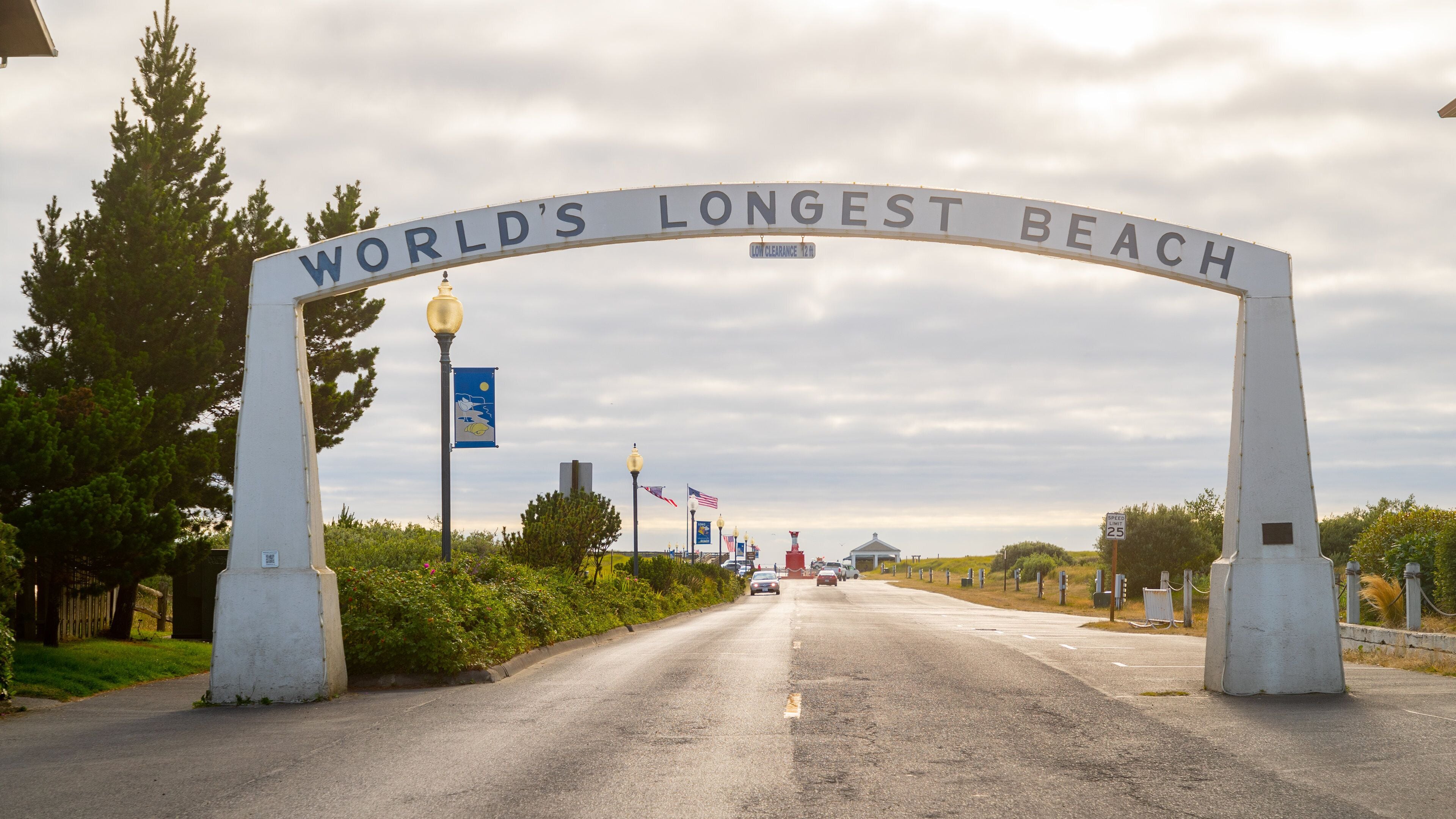Schild mit der Aufschrift 'Längster Strand der Welt', Geschwindigkeitsbegrenzungsschild und eine Straße mit Autos.