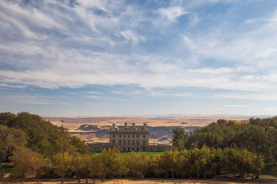A large building surrounded by trees and a vast landscape.