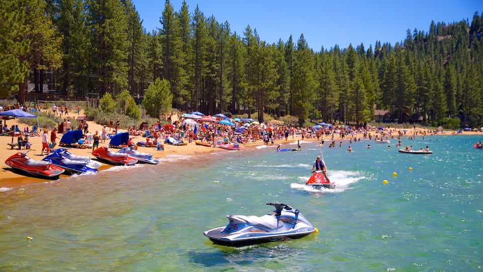 A crowded beach with jet skis and people enjoying the water.
