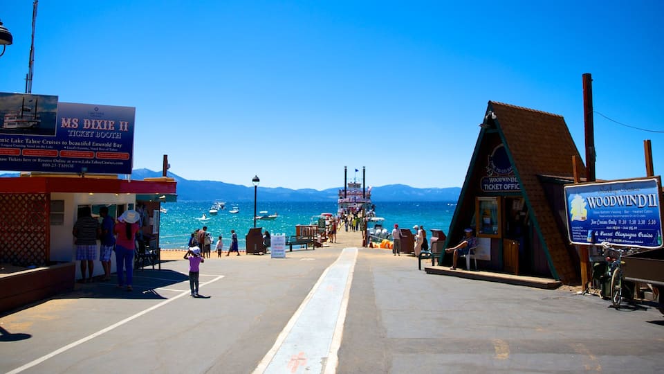 A pier with ticket booths for MS Dixie II and Woodwind II cruises, boats in the water, and mountains in the background.