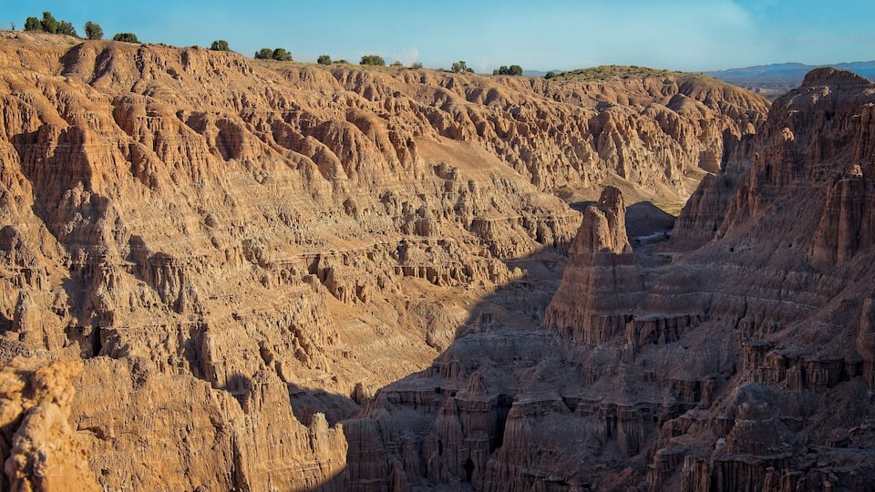 A rugged canyon with layered rock formations and sparse vegetation.