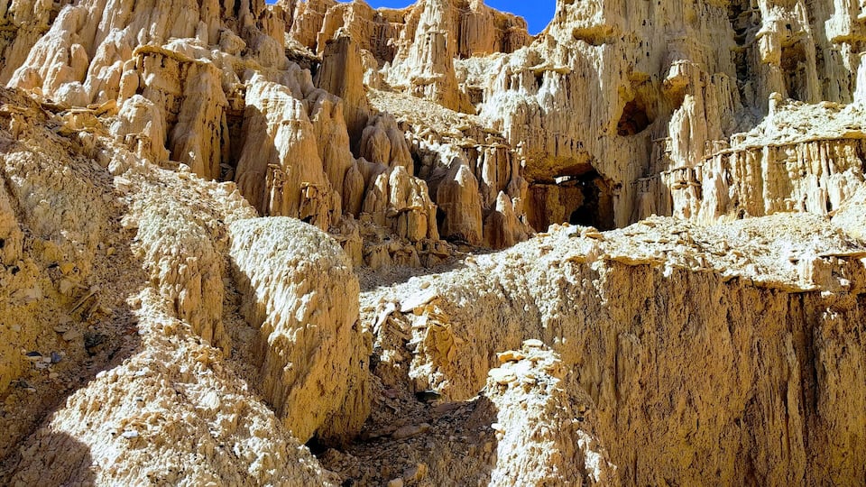 A rugged desert landscape with eroded rock formations and sparse vegetation.