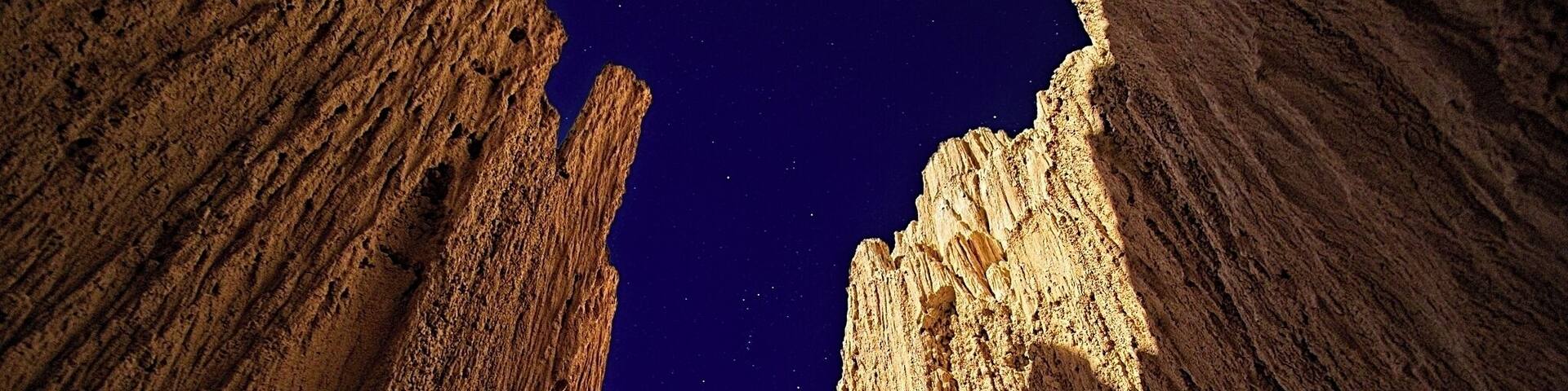 A canyon with steep rock walls and a starry night sky.