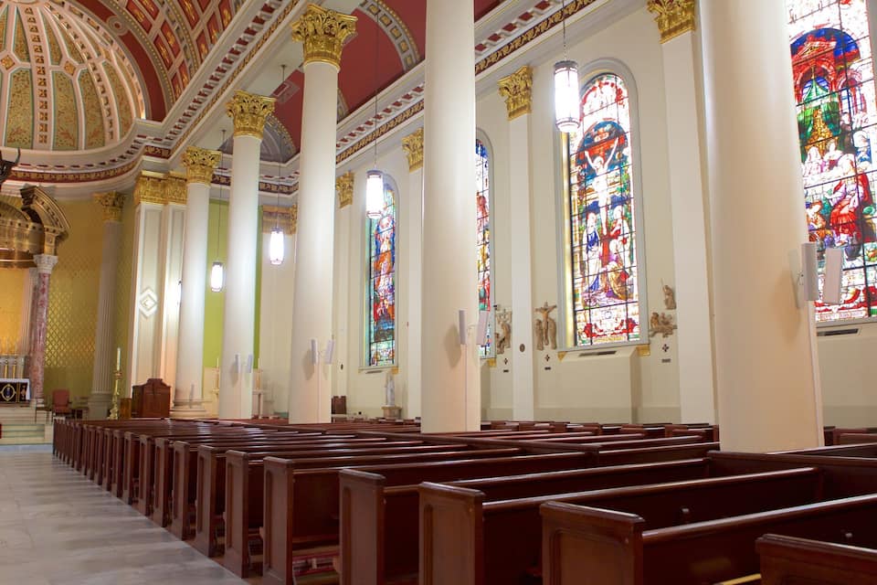 A church interior with rows of pews, stained glass windows, and a large dome ceiling.