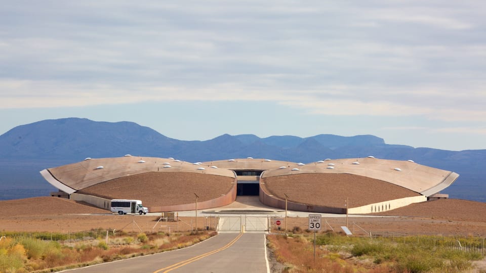 A unique building with a curved roof and a speed limit sign of 30.