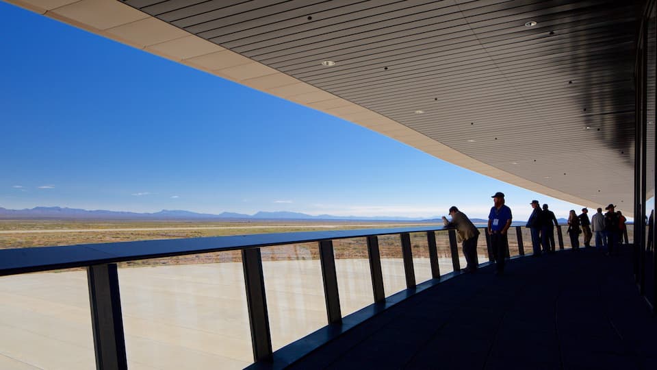 A group of people standing on a balcony overlooking a vast, flat landscape with distant mountains.