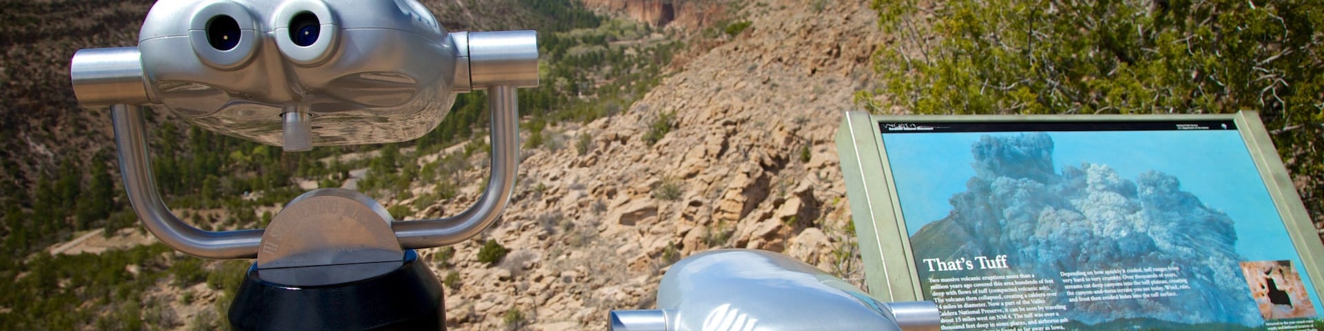 A pair of binoculars and a sign with information about a volcanic crater.