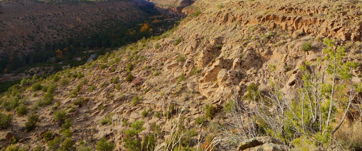 A rugged mountain landscape with sparse vegetation and a clear sky.