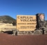 A sign for Capulin Volcano National Monument with a clear sky and a mountain in the background.