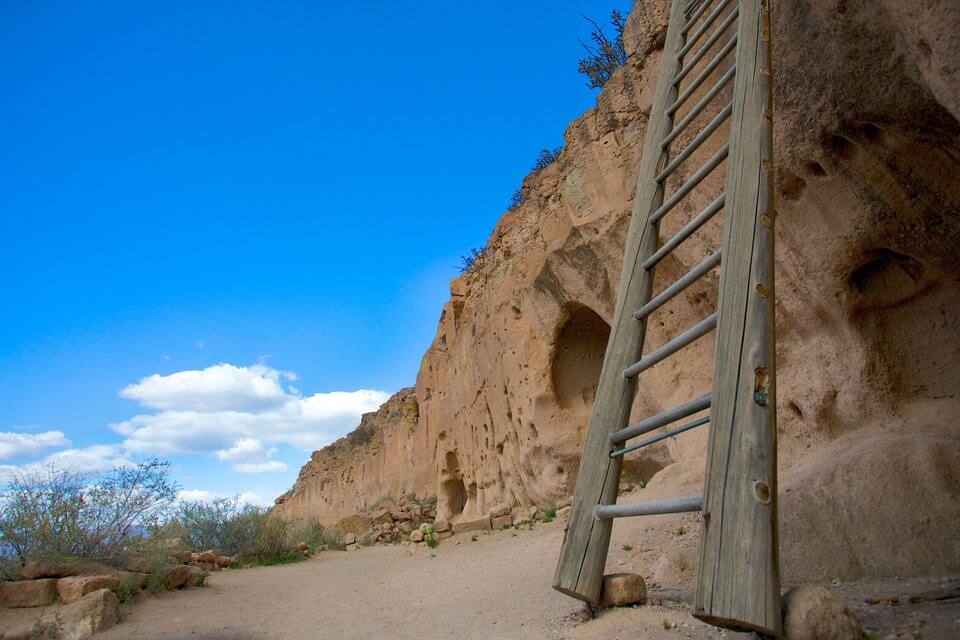 A wooden ladder against a rocky cliff under a clear blue sky.