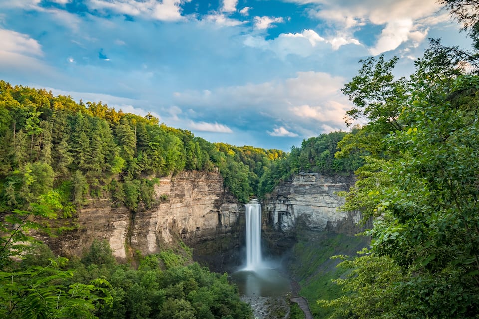 Ein Wasserfall stürzt über eine Klippe, umgeben von dichtem Wald.