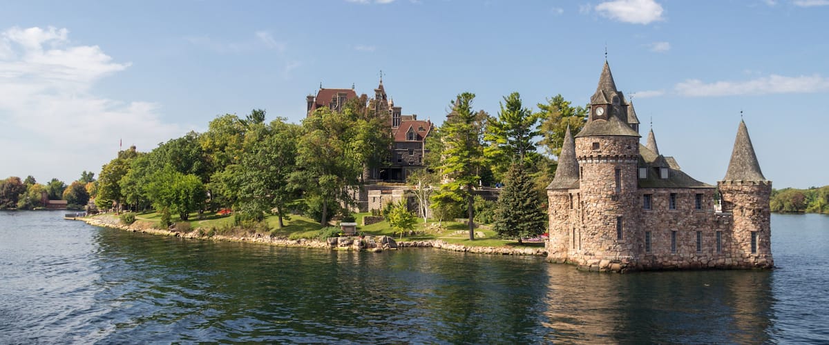 A historic stone castle on a lakeside island with a clear sky.