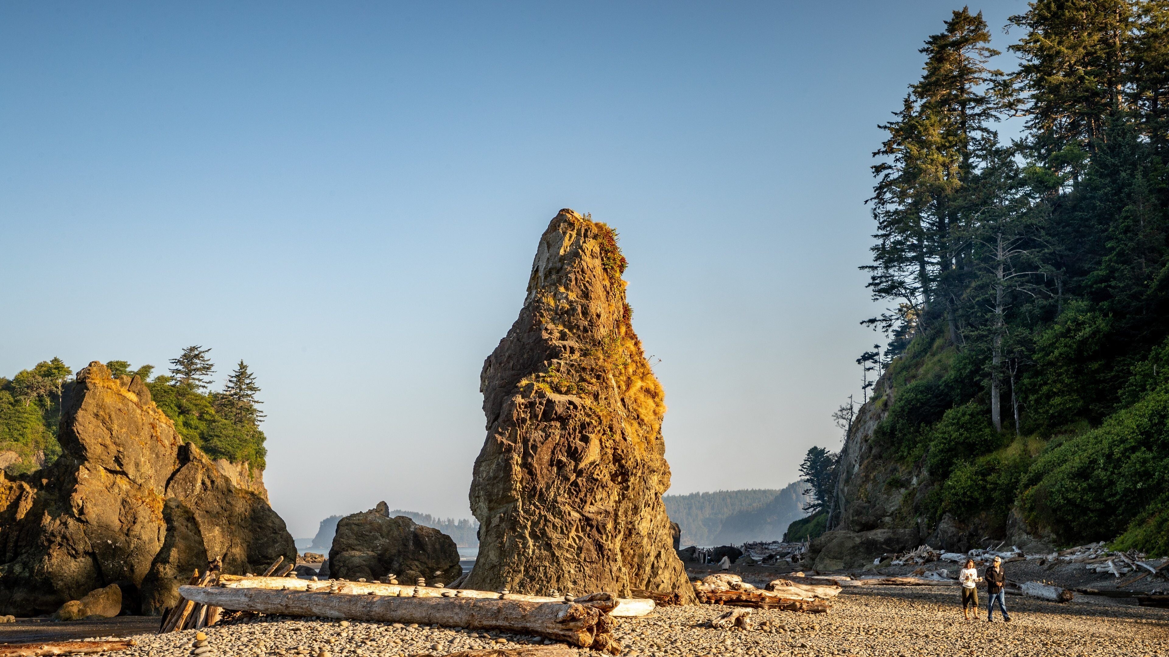 A rocky shoreline with large boulders and a prominent rock formation.