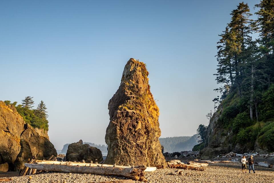 A rocky shoreline with large boulders and a prominent rock formation.