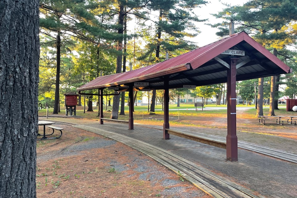 A covered train station with tracks and a sign reading "LAU CLAIRE".