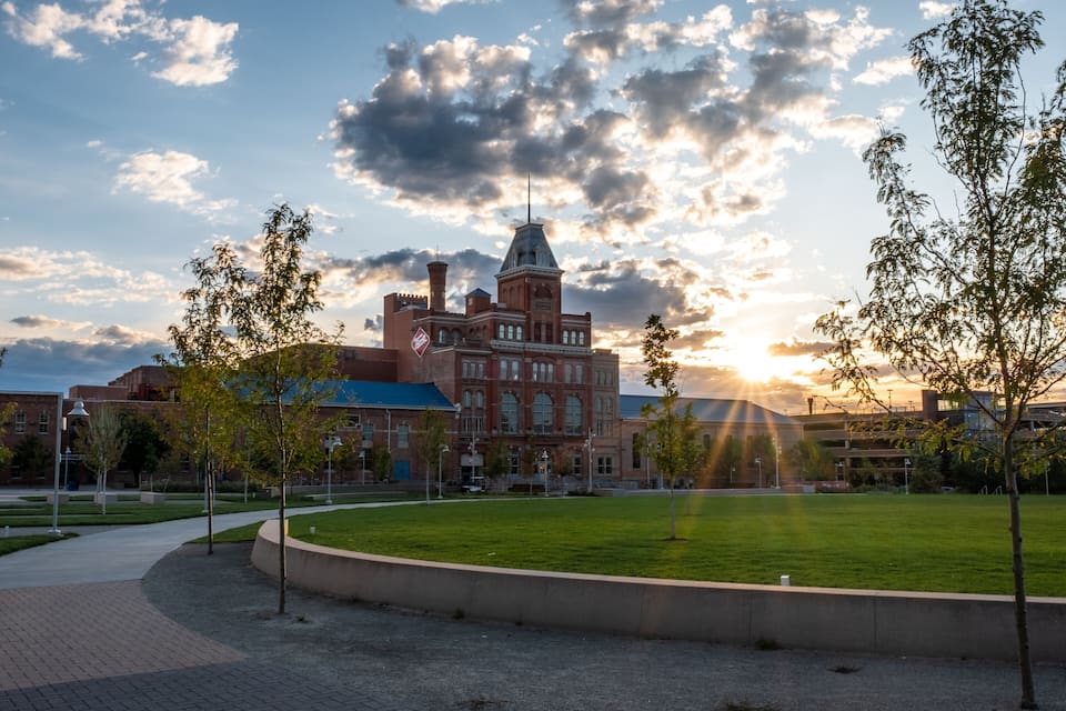 A historic building with a clock tower, surrounded by a grassy area and trees.