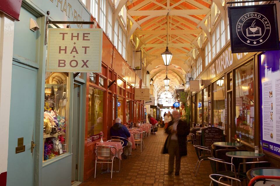 Ein schmaler Innenbereichs-Einkaufsgang mit Geschäften an beiden Seiten, darunter 'The Hat Box' und 'The Oxford Cafe'.