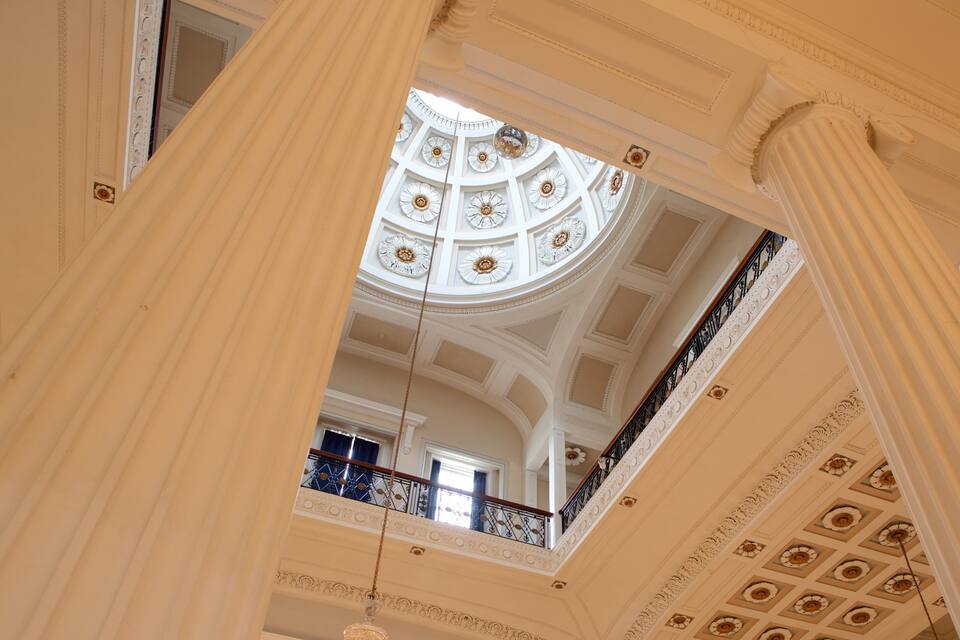 Un interior imponente con columnas ornamentadas, un techo abovedado y un balcón con barandilla.