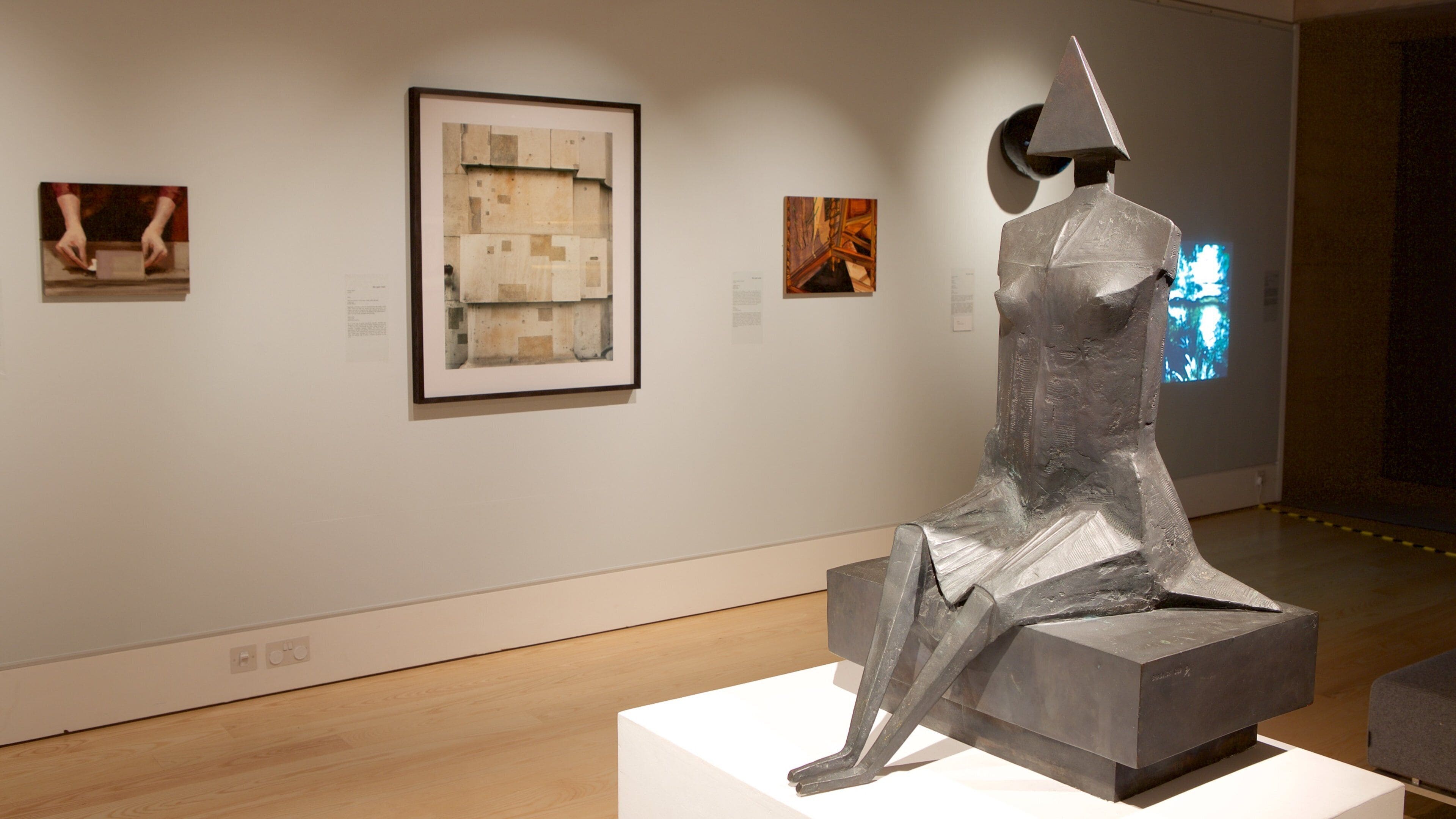 A sculpture in an art gallery with framed artworks on the wall.
