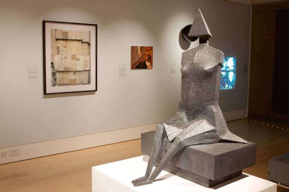 A sculpture in an art gallery with framed artworks on the wall.