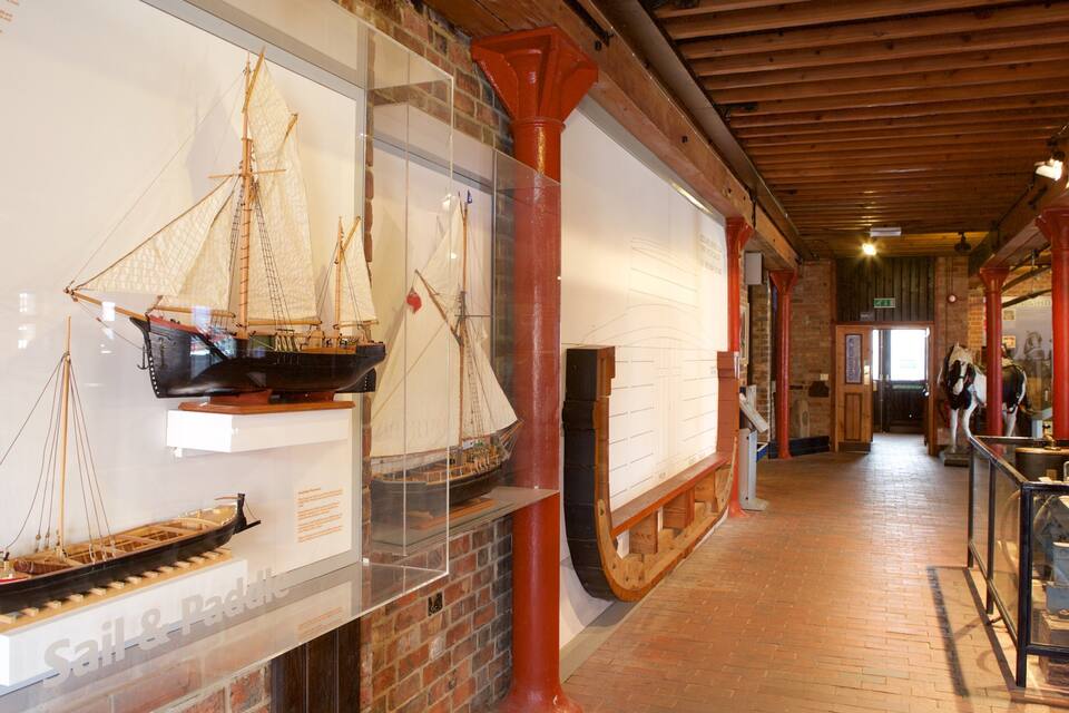 Una mostra de museu amb vaixells models i una paret de maó.