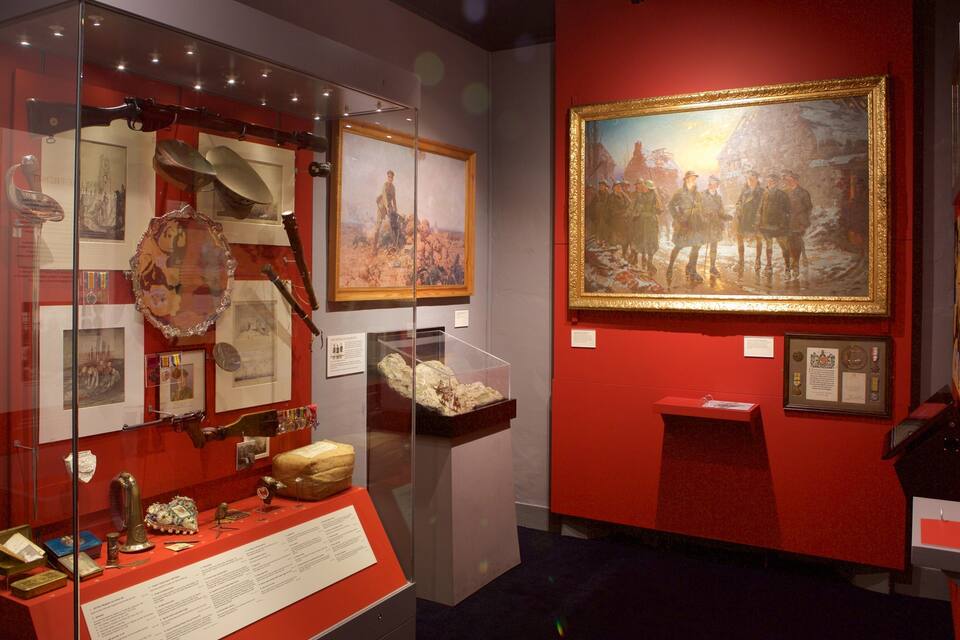 Una exposició de museu amb artefactes històrics, quadres emmarcats i un gran quadre de soldats.