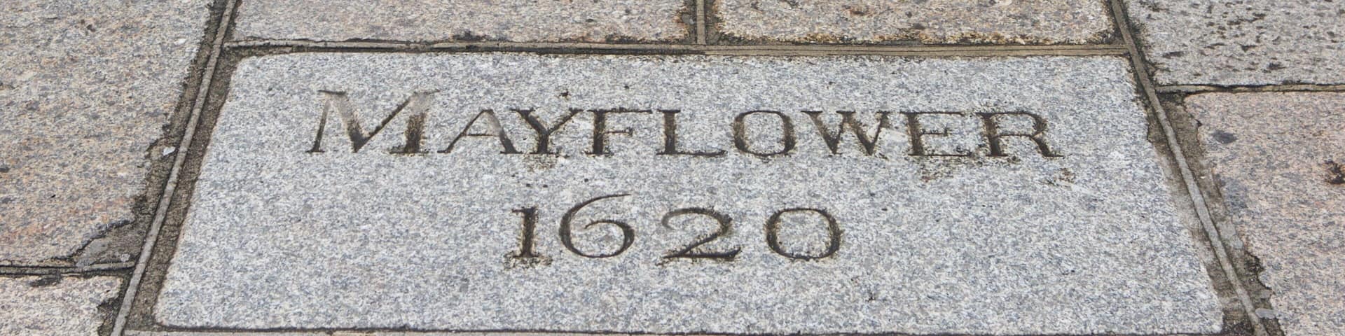 A stone plaque with the inscription "MAYFLOWER 1620" on a paved pathway.