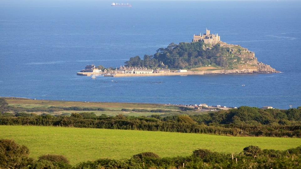 A coastal landscape with a prominent castle on a small island, surrounded by water and greenery.