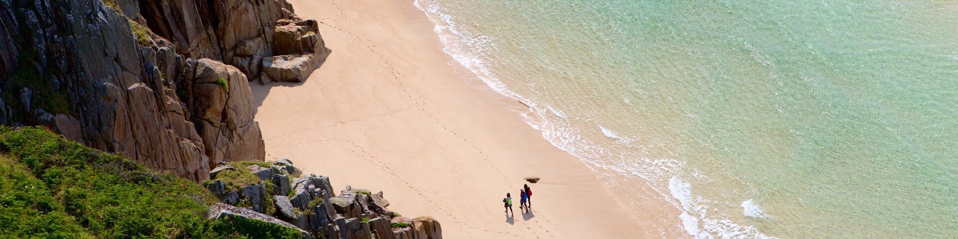 Porthcurno Beach ofreciendo una playa de arena y costa rocosa