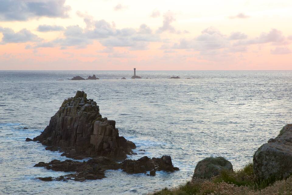 A rocky coastline with a lighthouse in the distance.
